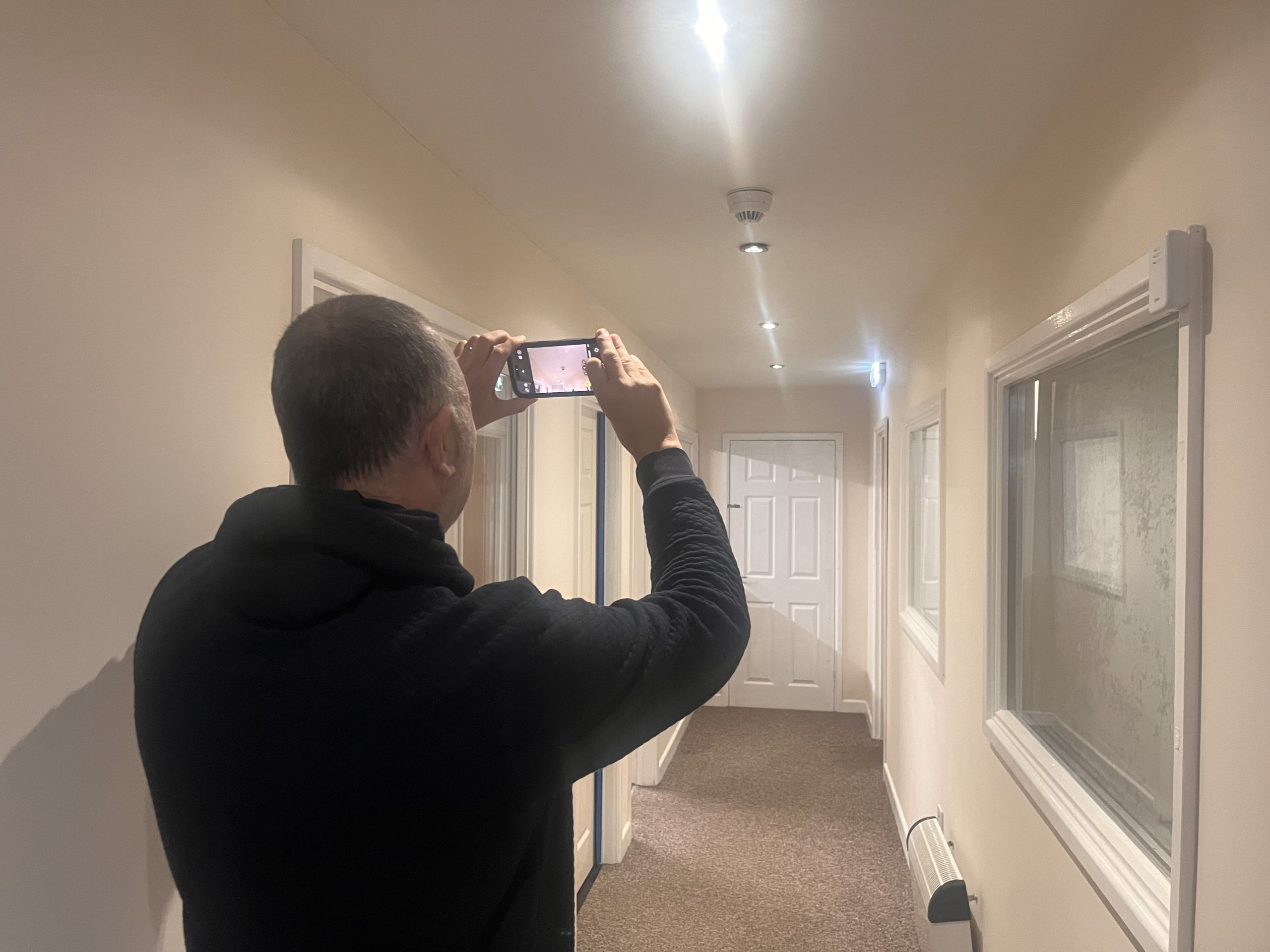 Fire risk assessor photographing a corridor and escape route during an assessment in Wales